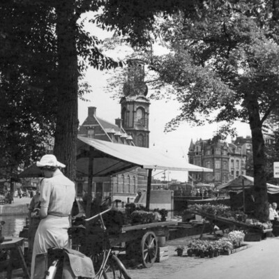 Woman with a bicycle at a large flower stall.