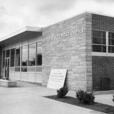 photo of one-story building of brick stone, and aluminum; "United States Post Office" is on front of stone front.