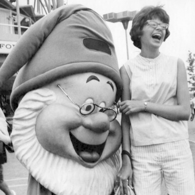 A laughing woman next to a cartoon character.