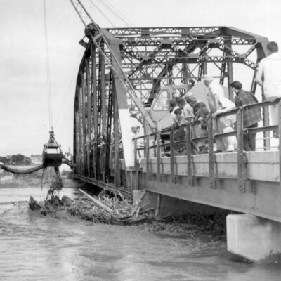 Flood debris under a railroad bridge over a river.