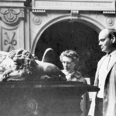 Two people looking at an ornate tomb.