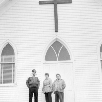 Three persons standing in front of a church.