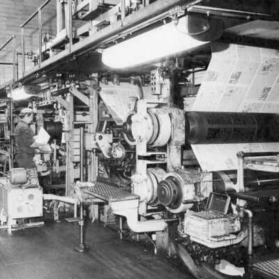 A man standing near a printing press.