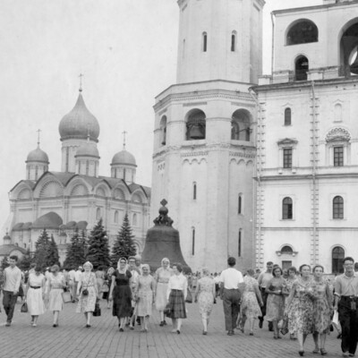 Tourists strolling brick street with large buildings in the background.