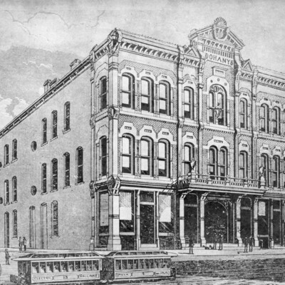 Engraving of old,  three-story brick building with two streetcars running in front of building.