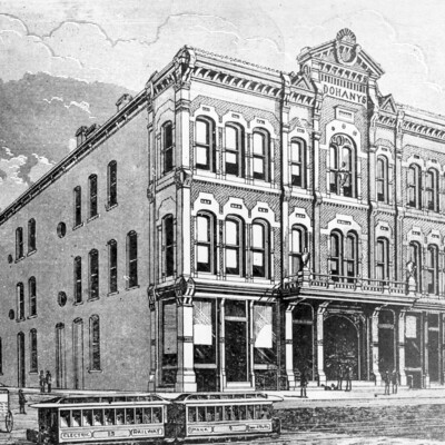 Engraving of old,  three-story brick building with two streetcars running in front of building.