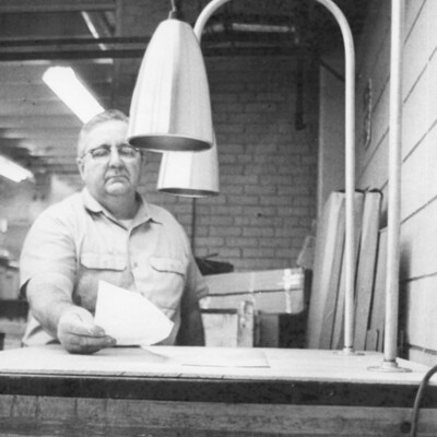 A man holding a piece of paper on a table under two lamps.
