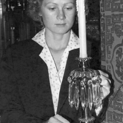 Woman stands behind antique candleholder with crystal tear drops.