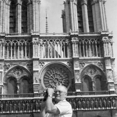 A man with a movie camera in front of a church.