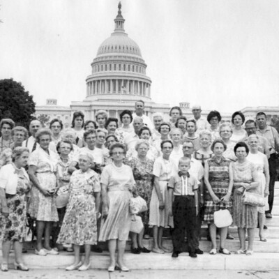 A group of tourists pose in front of the U.S. Capitol.