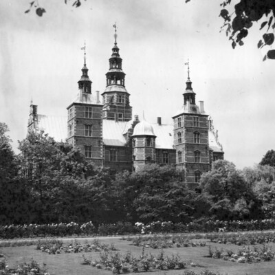 A castle surrounded by trees and flower gardens.
