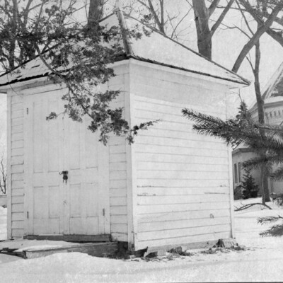 Tiny, square clapboard building with double wooden doors