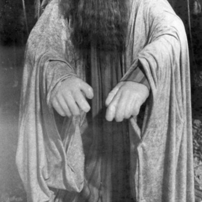 photo of wax figure dressed in robes, with box of gold coins