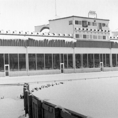 winter view of long building with many windows and doors, overlooking turn of a reacetrack