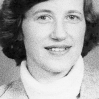 Head shot of woman with short, dark hair, wearing turtleneck sweater and jacket.
