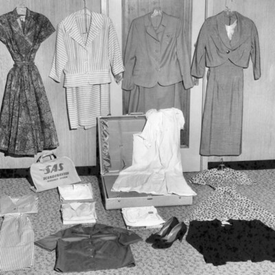 Open suitcase surrounded by women's clothing.