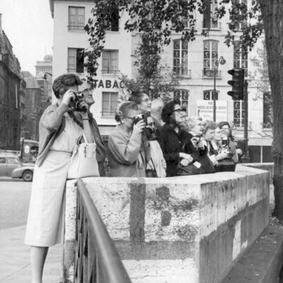 A line of women behind a barrier holding cameras.