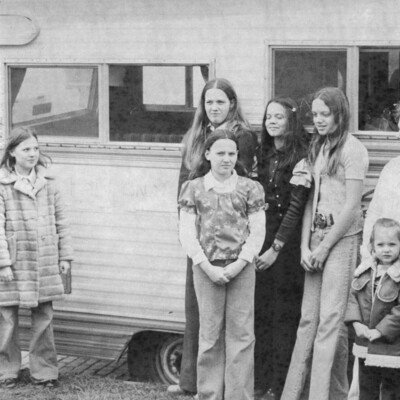 Eleven people, of various ages, next to an RV