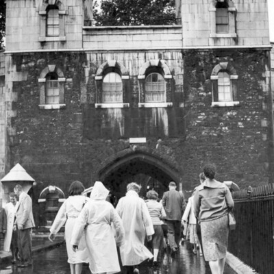 Tourists walking on a bridge under a fortress.