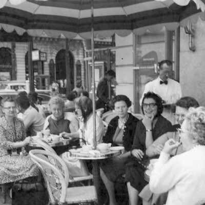 A group of women sitting outdoors under an umbrella table.