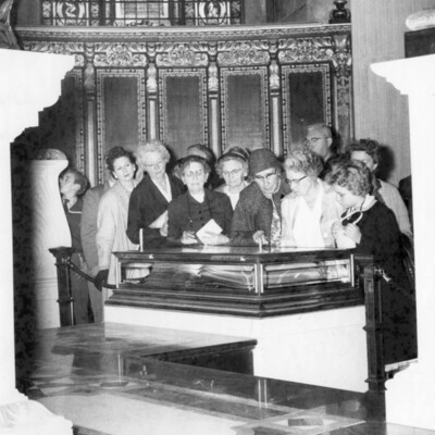 A group of women viewing a wooden and glass case.