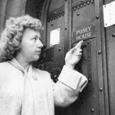 A woman pointing to a nameplate on a door.