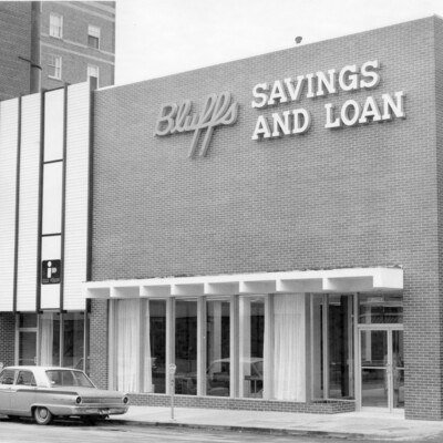 front facade of brick building with windows and overhang,  on city street