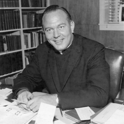 Man in clerical collar sitting at desk in an office