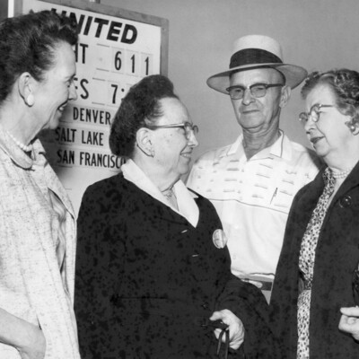 Three women and a man standing near an airline sign.
