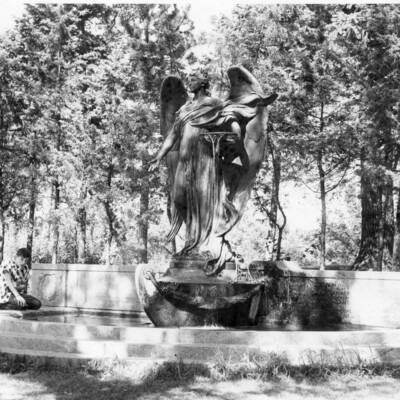 Large statue of angel in the bow of a boat, with short wall and collecting pool