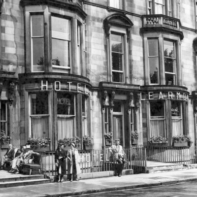 People standing and sitting in front of a hotel.