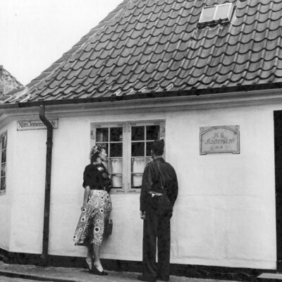 A man and woman looking through a home's window.