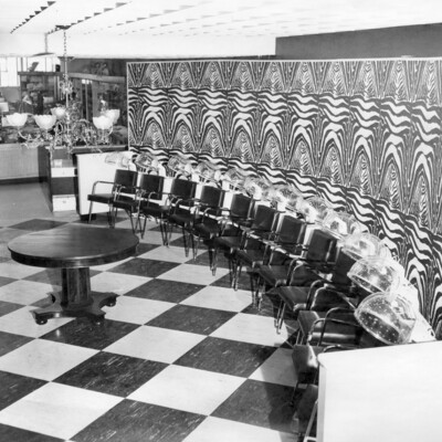 row of chairs with hair dryer hoods, along a decorated wall