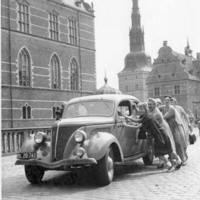 A group of women pushing a car.